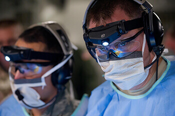 Zwei Ärzte mit Schutzbrillen und Stirnlampe forschen
