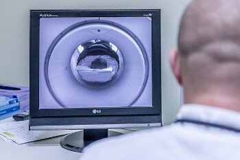 Ein Radiologe überwacht die Untersuchung eines Patienten im MRT über seinen Monitor